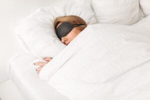 Lady wearing black eyes mask while sleeping in bed at home